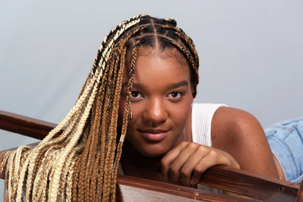 Guia completo de cuidados com tranças box braids Uma jovem com cabelo trançado, destacando sua beleza e estilo. A pose sugere uma conexão pessoal com a câmera e a expressão é confiante.