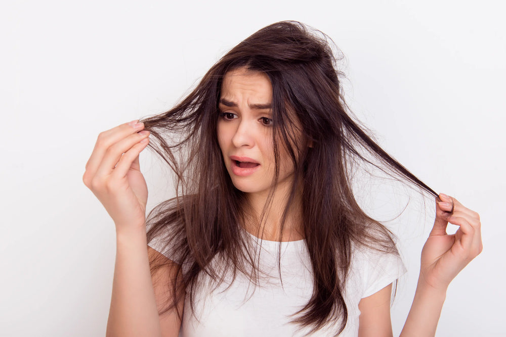 Cabelo fino e ralo: como identificar e tratar Mulher com cabelo bagunçado, demonstrando preocupação com os fios finos. A expressão facial transmite desconforto.