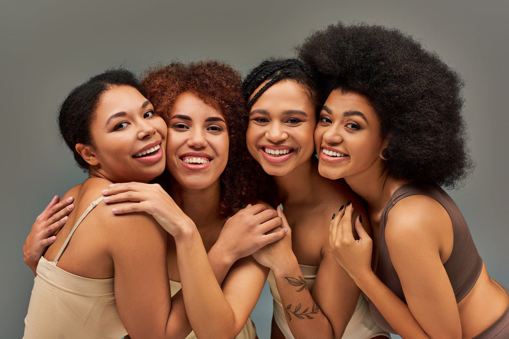 Cuidados com cabelo cacheado: guia prático pra cuidar dos seus cachos Grupo de mulheres sorrindo em harmonia, celebrando a beleza da diversidade e da amizade, com diferentes tipos de cabelo e tons de pele.
