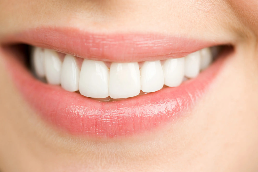 Dentes brancos? Qual a tonalidade ideal? Sorriso radiante com dentes brancos e saudáveis, destacando a importância da higiene bucal e cuidados dentários para um sorriso perfeito.