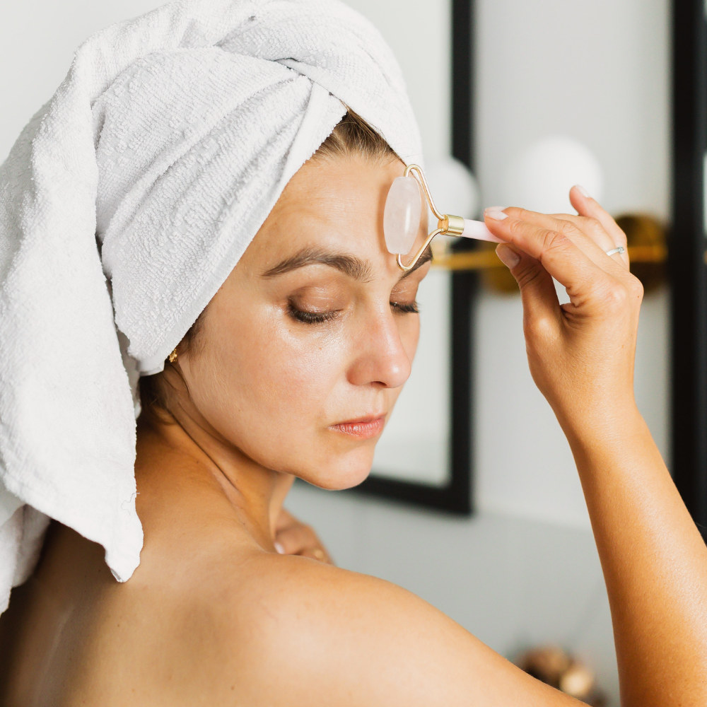 mulher com toalha na cabeça fazendo massagem no rosto