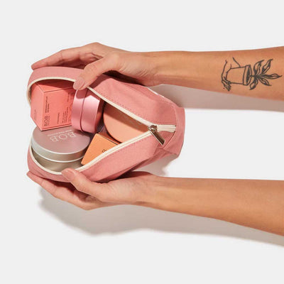 mulher com tatuagem no braço segurando necessaire rosa