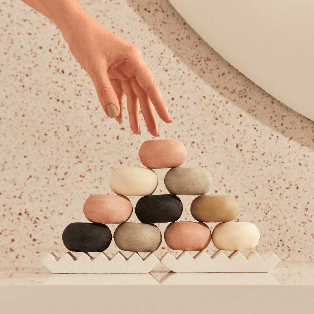 pilha com sabonetes coloridos em barra e mão indo segurar 