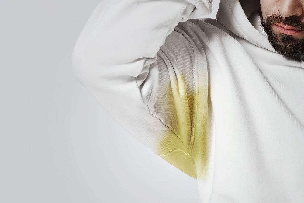 Homem usando um moletom branco com uma mancha amarela na área da axila.