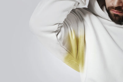 Homem usando um moletom branco com uma mancha amarela na área da axila.