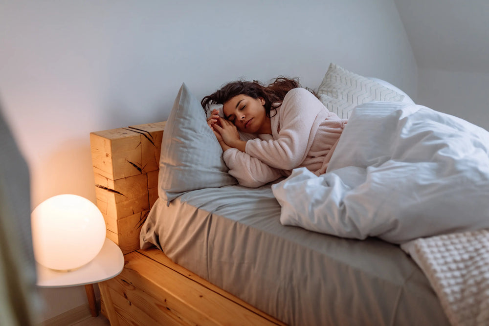 Uma jovem dormindo tranquilamente em uma cama confortável com lençóis brancos, criando um ambiente aconchegante e relaxante.
