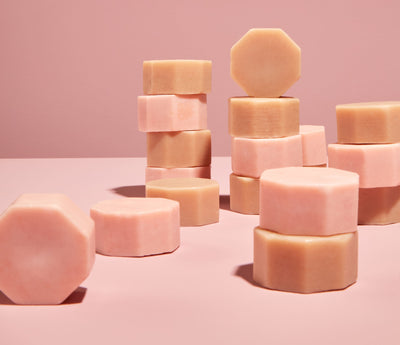 Imagem de diversas barras de máscara capilar espalhadas em uma superfície rosa. 