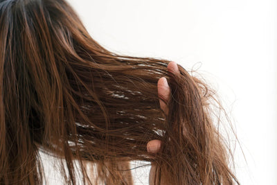 Imagem de uma pessoa segurando seus cabelos longos e soltos, evidenciando a textura e o brilho dos fios.