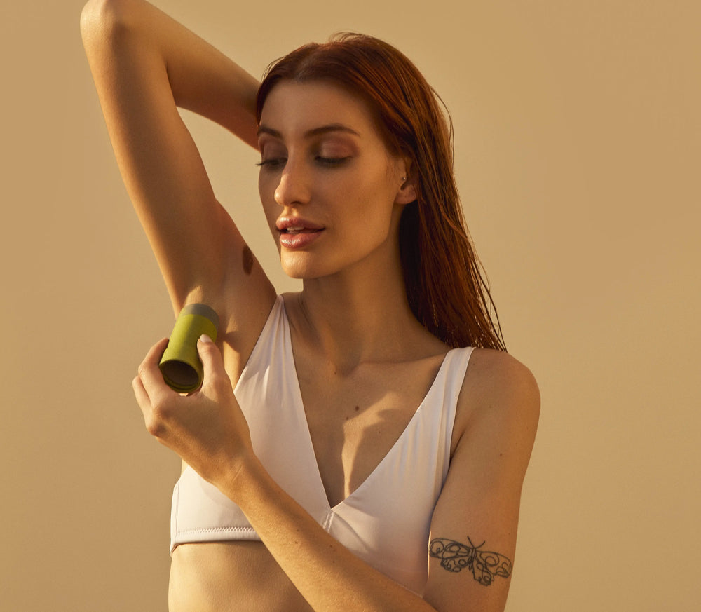 Modelo utilizando produto de cuidados pessoais para axilas, mostrando atenção à beleza e cuidados com a pele.