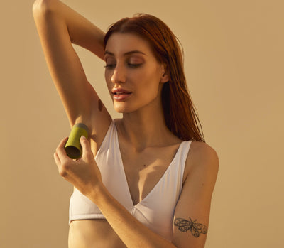 Modelo utilizando produto de cuidados pessoais para axilas, mostrando atenção à beleza e cuidados com a pele.