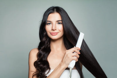 Mulher com cabelo liso, usando uma chapinha para alisar os cabelos longos e saudáveis, apresentando um sorriso e um visual moderno.