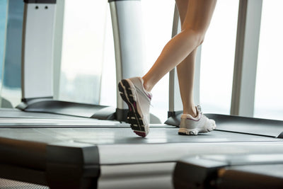 Mulher correndo na esteira em um ambiente moderno de academia, destacando a importância de se manter ativo.