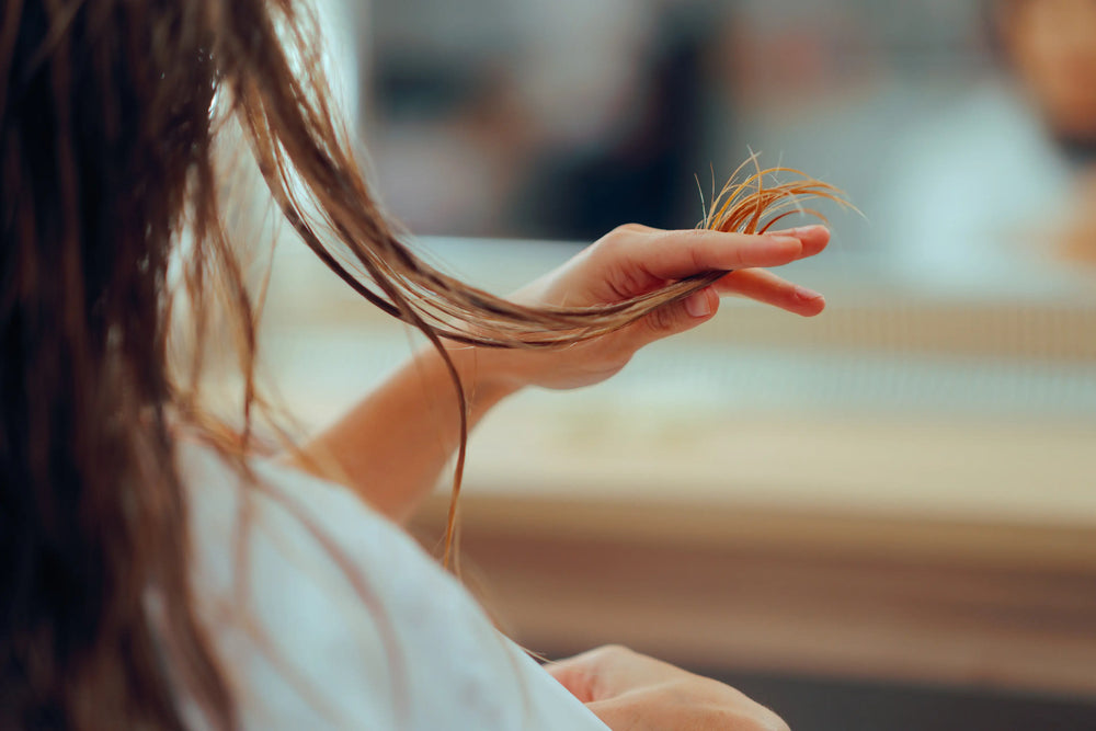 Mulher examinando mechas de cabelo em um salão de beleza, simbolizando cuidado e estilo capilar. Destaque para a textura e aparência dos fios.