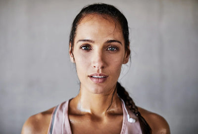 Mulher com aparência determinada e focada após exercícios físicos, com suor aparente no corpo.