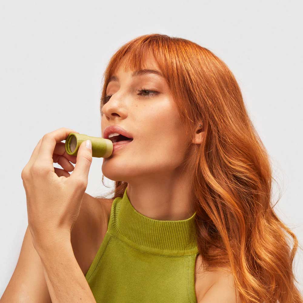 Pessoa segurando o novo hidratante labial da B.O.B e passando sobre o lábio inferior