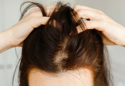 Mulher segurando os cabelos na raiz, evidenciando a saúde do cabelo e o cuidado capilar.